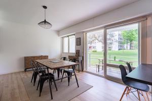 a dining room with a table and chairs and a large window at Appartement d'exception proche des commerces avec piscine in Biarritz