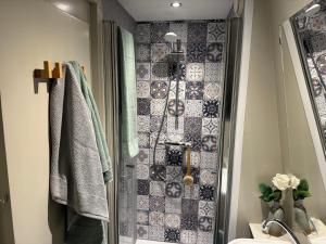 een badkamer met een douche en een betegelde muur bij Hotelhuisjes Medemblik in Wieringerwerf