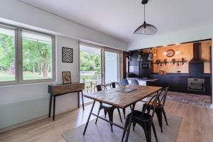 a kitchen and dining room with a wooden table and chairs at Appartement d'exception proche des commerces avec piscine in Biarritz