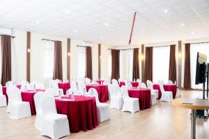 a room with red and white tables and white chairs at West Wood Hotel in Nairobi