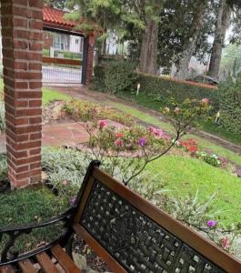um banco sentado num jardim com flores em Apartamento Aconchego Gramado em Gramado