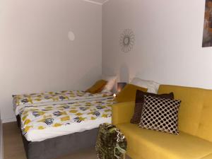 a bedroom with a bed and a yellow couch at BROWARNA apartamenty Tanie Spanie in Elblag