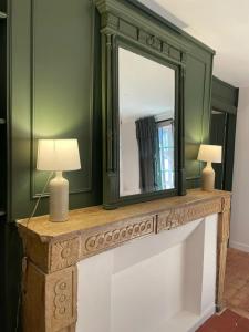 a mirror on a mantle with two lamps on it at Les appartements d'Albertine - Clémence in Bourges