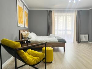 a bedroom with a bed and a yellow chair at Квартира в ЖК USOLKA CITY in Pavlodar