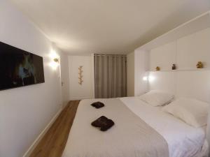 una camera da letto bianca con un grande letto bianco con due scarpe marroni sopra di L instant Chaumois - Moment zen aux Sables d Olonne a Les Sables-dʼOlonne