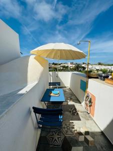 einen Tisch und Stühle auf einem Balkon mit Sonnenschirm in der Unterkunft Ventotene La casa in Piazza in Ventotene