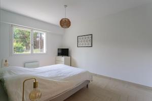 a white bedroom with a bed and a window at Appartement d'exception proche des commerces avec piscine in Biarritz
