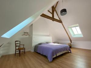 a bedroom with a bed and a chair in a attic at Gîte 11 personnes en pleine campagne in Sainte-Anne-sur-Vilaine