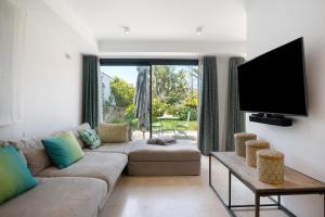uma sala de estar com um sofá e uma televisão de ecrã plano em Light house em Conil de la Frontera