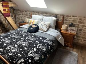 ein Schlafzimmer mit einem Bett mit einer schwarzen und weißen Decke in der Unterkunft Le Terrier, chambre d'hôte à thème Le sorcier à lunettes 