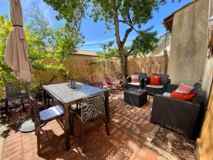 a patio with a table and chairs and an umbrella at Agréable maison rénovée in Lacanau-Océan