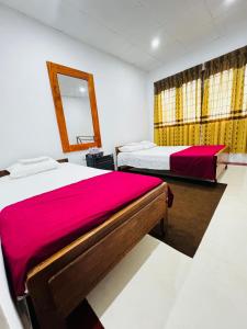 a bedroom with two beds and a mirror and a mirror at Prestiva Stay in Anuradhapura