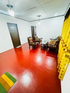 a living room with a red floor and chairs at Prestiva Stay in Anuradhapura