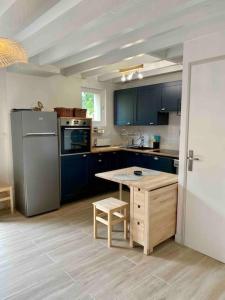 a kitchen with blue cabinets and a table in it at Agréable maison rénovée in Lacanau-Océan +15 photos