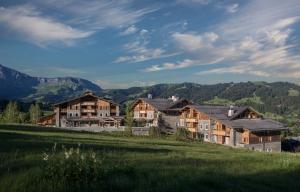 een groep huizen in een veld met bergen op de achtergrond bij Four Seasons Hotel Megeve in Megève