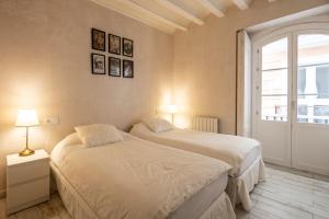 two beds in a room with a window at Plaza San Antonio, Casa Bugambilla in Cádiz