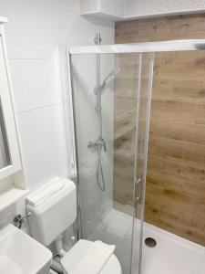 a white bathroom with a shower and a toilet at Bed & Bike Zagreb studio apartment in Zagreb