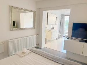 biały pokój z lustrem i telewizorem w obiekcie Bed & Bike Zagreb studio apartment w Zagrzebiu