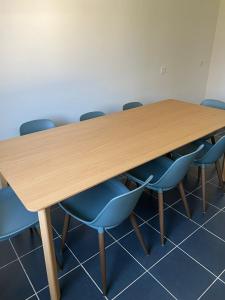 une salle de conférence avec une table en bois et des chaises bleues dans l'établissement Ferienglück am Spielplatz, à Guntzbourg