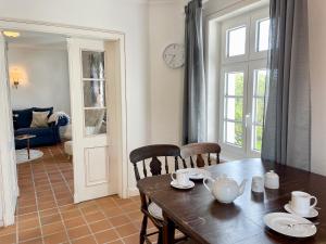 a dining room with a table and chairs and a clock at Landhaus Tons 4 Tinje in Keitum