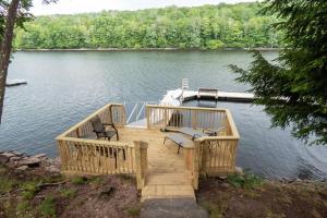 ein Holzsteg mit zwei Stühlen und einem Boot auf einem See in der Unterkunft Lakefront Haven Home in Monticello