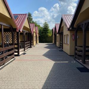 a walkway between two buildings with red roofs at Domki u Marcina in Sarbinowo