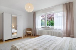 ein weißes Schlafzimmer mit einem Bett und einem Fenster in der Unterkunft Ferienwohnung Am Buchbühl in Stockach