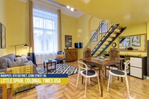 a living room with a table and chairs and a staircase at Little Americas Colonial Times Apts in Budapest