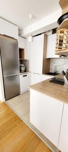 cocina con armarios blancos y nevera de acero inoxidable en Chic & Cosy apartment - 60m2, 3 rooms, en Asnières-sur-Seine