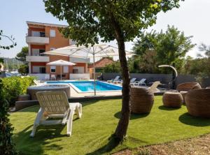 a yard with a swimming pool with chairs and a tree at M & B in Bibinje