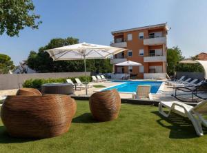 a pool with chairs and an umbrella next to a building at M&B Green Oasis with pool and jacuzzi in Bibinje