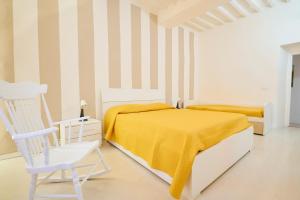 ein weißes Schlafzimmer mit einem gelben Bett und einem weißen Stuhl in der Unterkunft Casalsole Piombino in Piombino