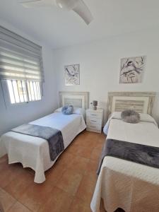 2 camas en una habitación con paredes blancas en Casa Rural La Escapadita en Benaoján