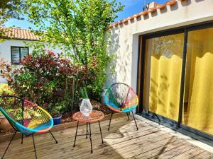 three chairs and a table on a wooden deck at Les Iris in Les Herbiers