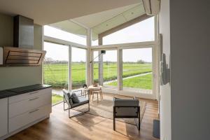 a kitchen with a large window with a table and chairs at Aan de Amstel in De Kwakel