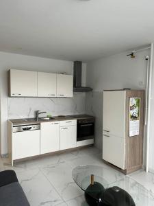 a kitchen with white cabinets and a glass table at Renewed 2 Bedroom Apartment with Parking in Ljubljana