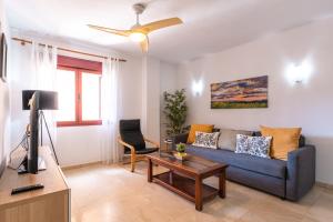 a living room with a blue couch and a tv at VILOS LAS CANTERAS in Las Palmas de Gran Canaria