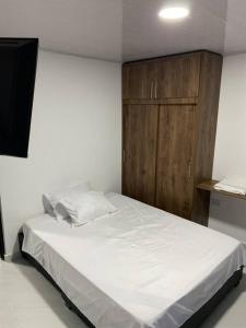 Schlafzimmer mit einem weißen Bett und einem Holzschrank in der Unterkunft Apartaestudio de una habitación central in Popayan