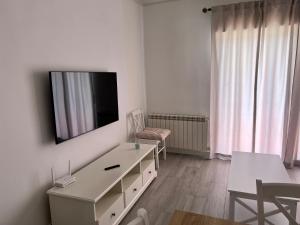 una sala de estar blanca con TV en la pared en El descanso de la Covatilla, en Béjar