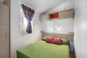a bedroom with a green bed with a window at Bungalow Cádiz Costa in Chiclana de la Frontera