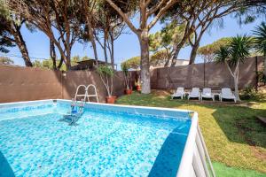 a swimming pool in a yard with chairs and trees at Bungalow Cádiz Costa in Chiclana de la Frontera