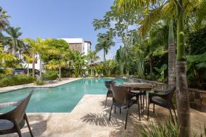 a pool with chairs and a table in front of a resort at Apartamento en Residencial Jardines de Monserrat in Las Terrenas