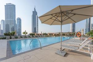 een zwembad met een parasol en een stoel naast een gebouw bij Stayis - 1 BR Near Burj Khalifa in Dubai