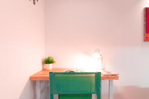 een groene stoel aan een bureau met een lamp bij EDomus Duque Boutique in Sevilla