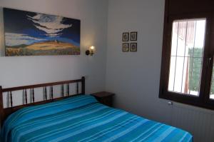 Schlafzimmer mit einem Bett mit blauer Bettwäsche und einem Fenster in der Unterkunft Haus LE COQ in L'Escala