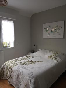 um quarto com uma cama com uma colcha branca e uma janela em Chambre chez l'habitant em Péronne