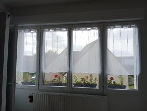 três janelas com cortinas brancas e vasos de plantas em Chambre chez l'habitant em Péronne