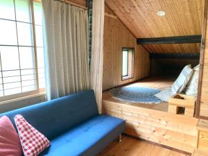 Habitación con sofá azul en una casa de madera en 田舎の別荘 かすみ草 en Shōgahora