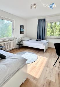 een slaapkamer met 2 bedden en 2 ramen bij BEGE APARTMENTS Business Residence in Hagen