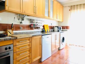 a kitchen with wooden cabinets and a white dishwasher at Apartamento T2 - Grândola Vila Morena in Grândola